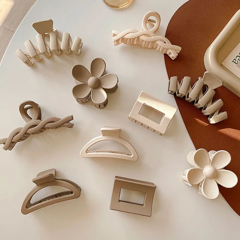 Collection of elegant hair claw clips in neutral tones, featuring floral and geometric designs on a stylish table.