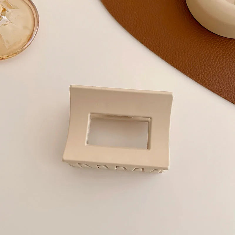 Elegant beige hair claw clip on a rustic surface, perfect for styling and securing hair in various looks.