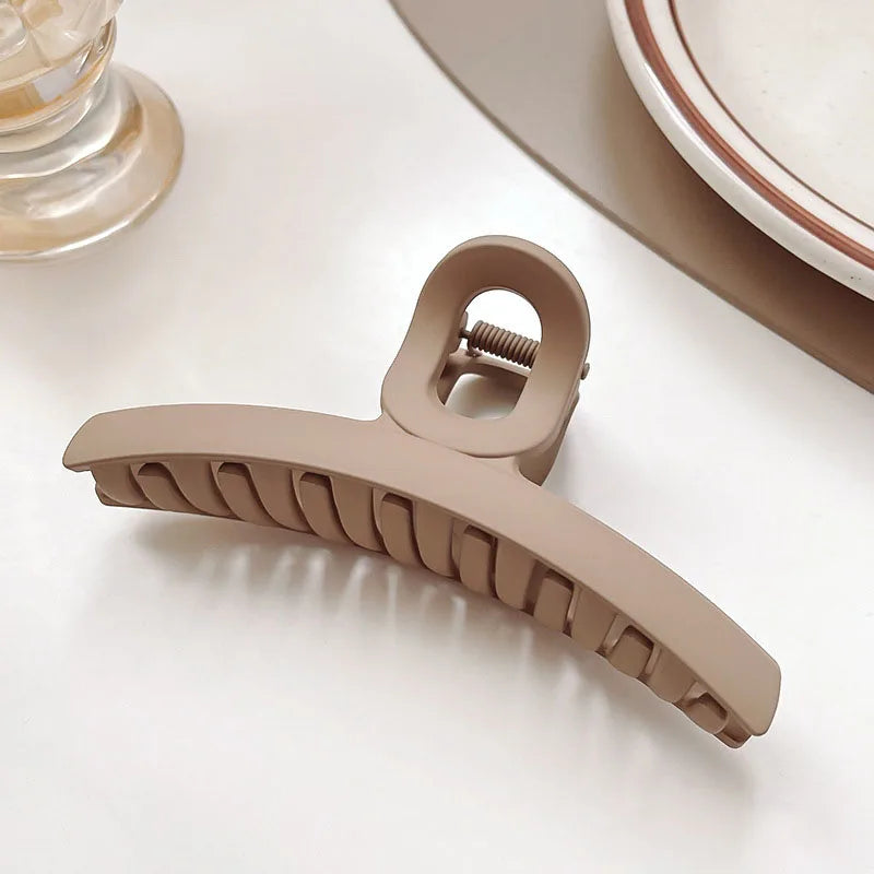 Women’s elegant beige hair claw clip on a table, perfect for securing hairstyles with a chic design.