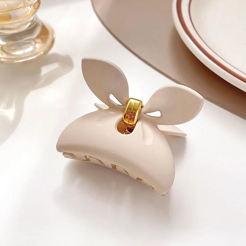 Women’s elegant beige hair claw with floral design and gold accent, perfect for secure hairstyles.