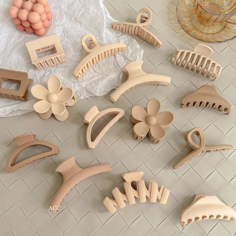 Collection of elegant beige and brown hair claw clips in various shapes on a textured surface.