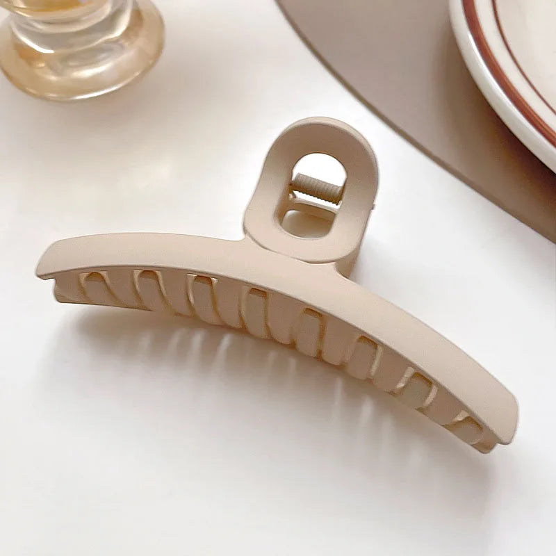 Elegant beige hair claw clip with solid teeth, ideal for securing hairstyles like buns and twists.
