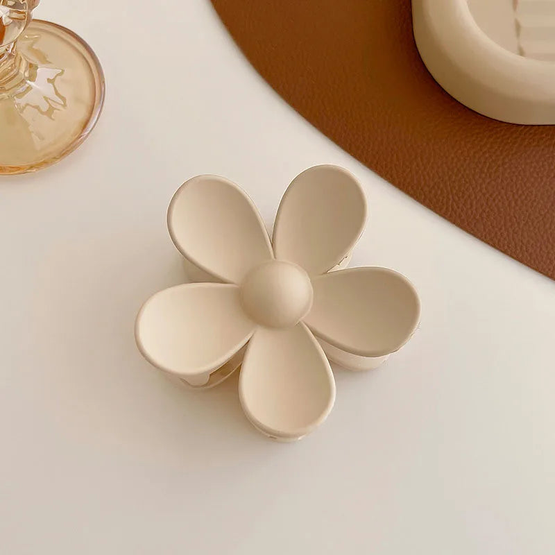Elegant beige floral hair claw on a stylish table, perfect for secure and fashionable hair styling.