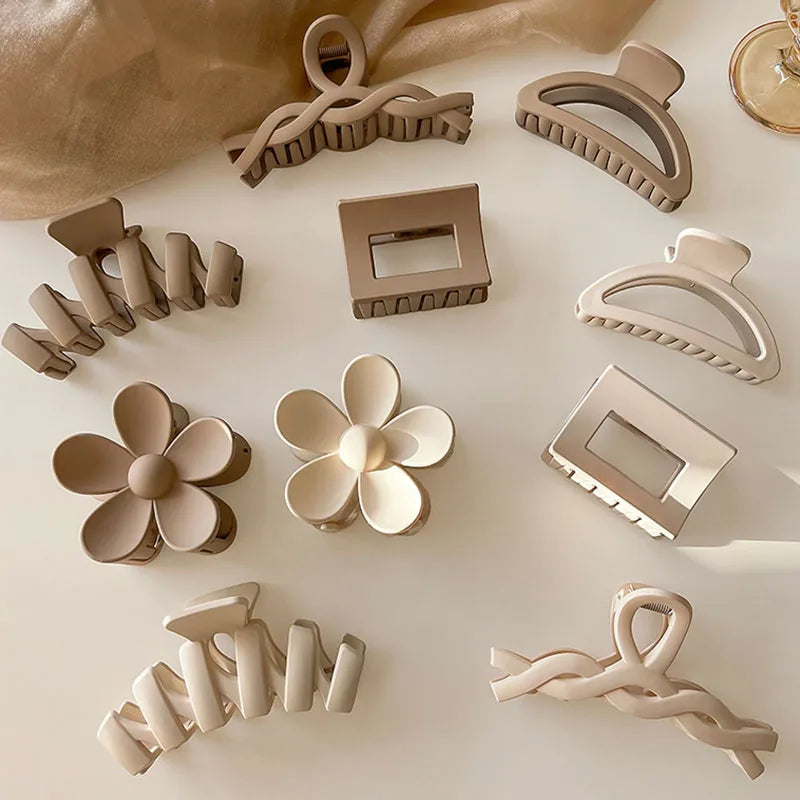 Collection of elegant brown and beige floral and geometric hair claws on a light background, showcasing stylish hair accessories.