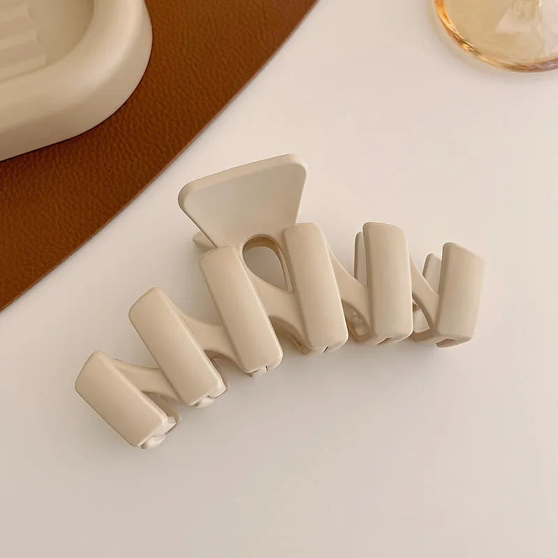 Women’s geometric beige hair claw clip on a stylish surface, perfect for securing hair in elegant updos.