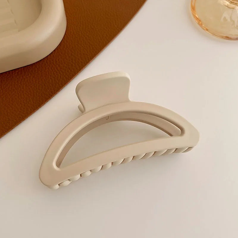 Elegant beige hair claw clip on a textured surface, perfect for stylish hair updos.