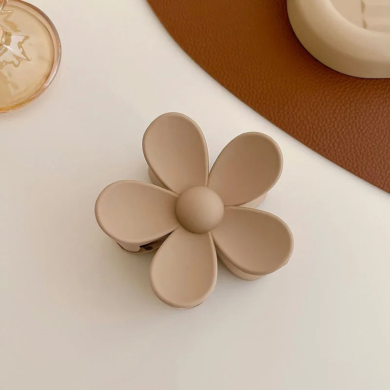 Women’s beige floral hair claw clip on a table, perfect for stylish hair updos and everyday elegance.
