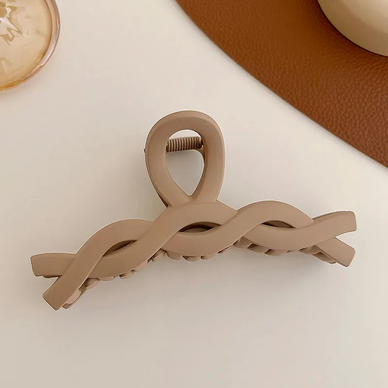 Elegant solid beige hair claw clip with twisted design on a light background, perfect for versatile hairstyles.