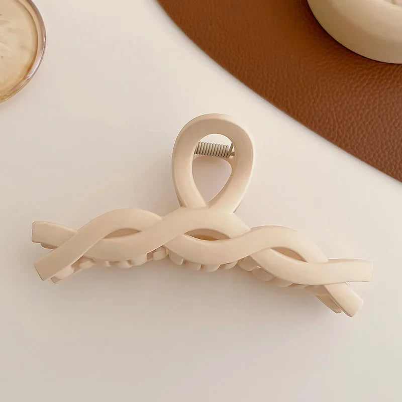 Elegant beige hair claw clip with a twisted design, perfect for securing hairstyles.