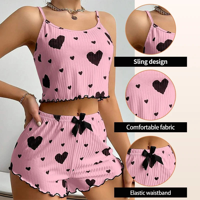 Women's pink pajama set with heart print, featuring a sling top and shorts with elastic waistband for summer comfort.